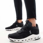 WhatsApp_Image_2024-11-07_at_12.03.07 | UAE SPORT STORE Black athletic sneakers with white chunky sole and On logo, worn with black leggings in a standing pose.