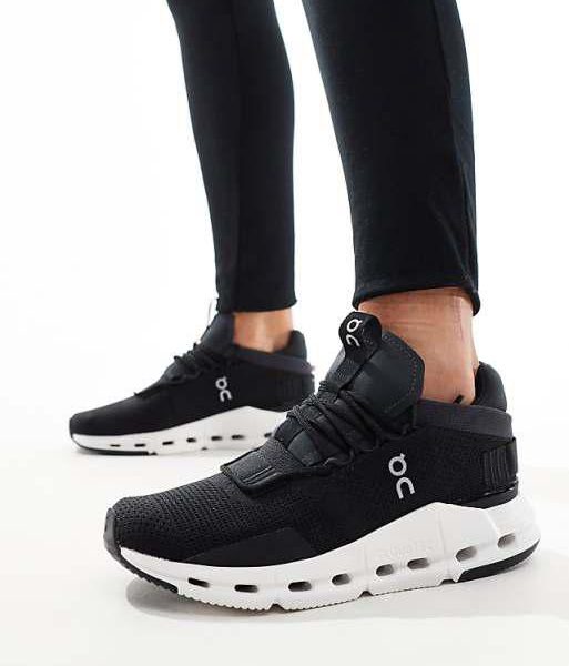 Black athletic sneakers with white chunky sole and On logo, worn with black leggings in a standing pose.