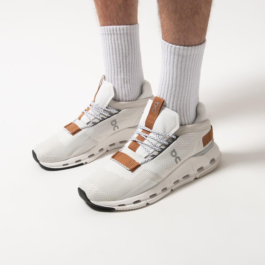 WhatsApp_Image_2024-11-07_at_14.08.37 | UAE SPORT STORE White athletic sneakers with tan-brown accents worn with light gray ribbed socks on a pale backdrop (showing a sporty lifestyle product).
