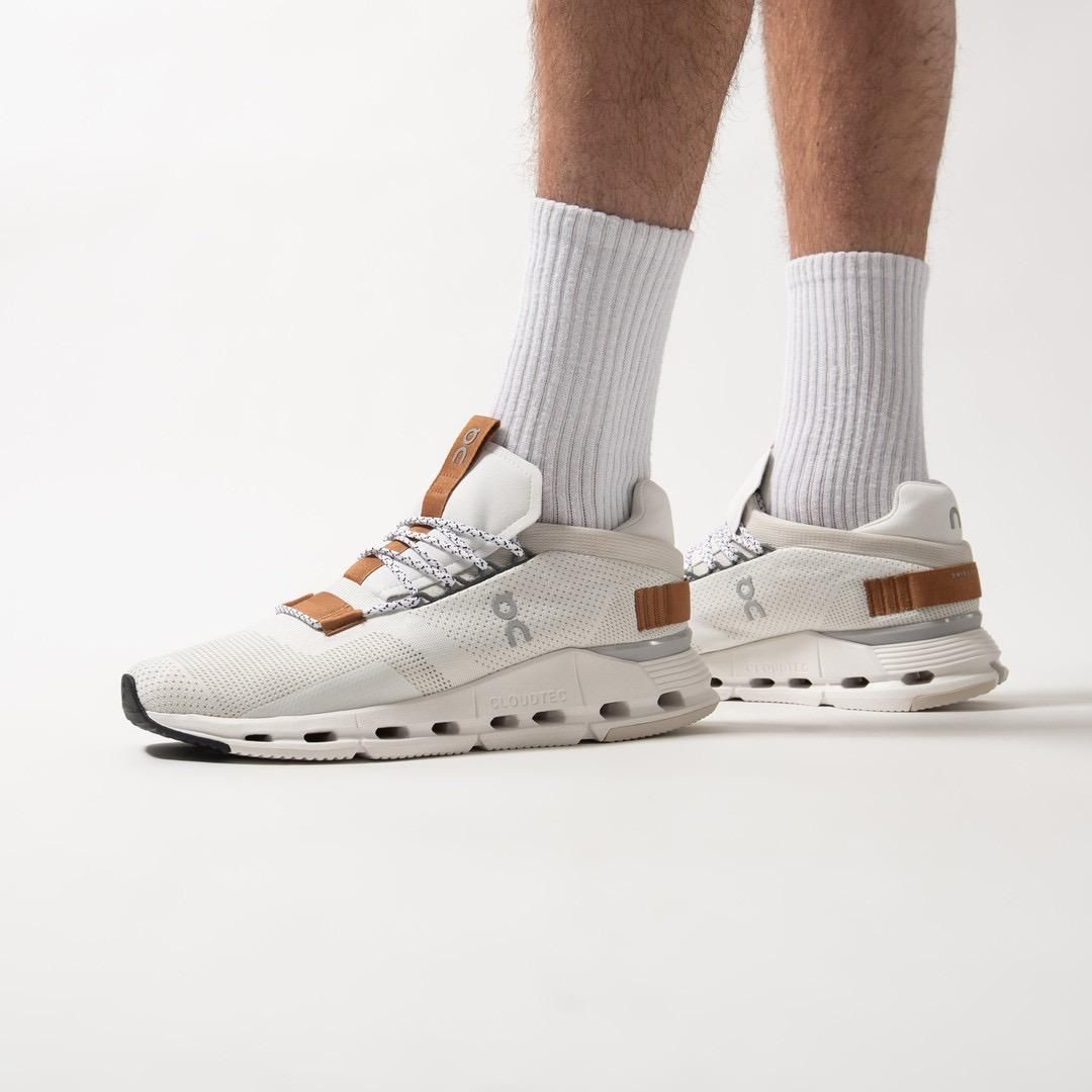 WhatsApp_Image_2024-11-07_at_14.08.44 | UAE SPORT STORE Pair of cream-colored running sneakers with brown leather straps and gray laces, worn with light gray ribbed socks on a white backdrop, showing a chunky midsole.