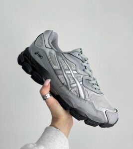 WhatsApp_Image_2024-11-08_at_11.04.49 | UAE SPORT STORE Gray Asics running shoe held in a hand against a plain background, showing the side and laces.