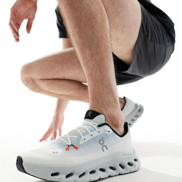Close-up of a person in white athletic sneakers in a crouched starting position for a run.
