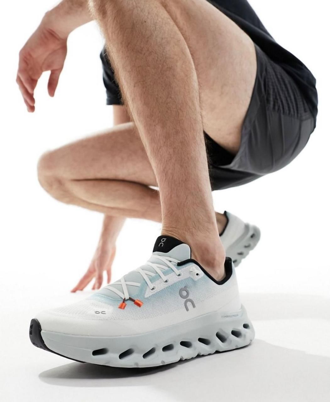 WhatsApp_Image_2024-11-09_at_13.00.25 Close-up of a person in white athletic sneakers in a crouched starting position for a run.