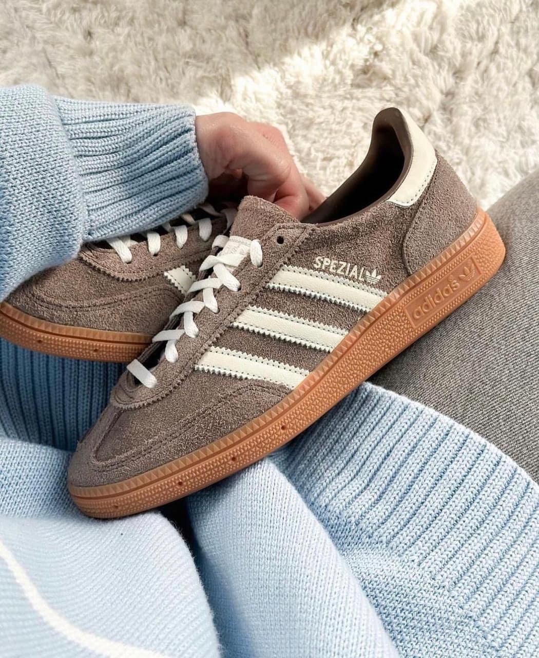 WhatsApp_Image_2024-11-22_at_11.10.51 | UAE SPORT STORE Brown suede Adidas Spezial sneaker with white stripes and gum sole, resting on a light blue knit fabric.