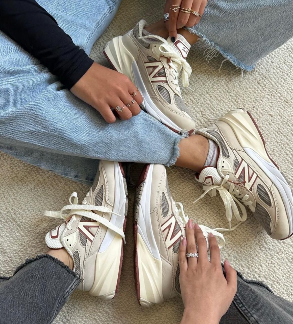 WhatsApp_Image_2024-12-04_at_12.23.56 | UAE SPORT STORE Two people wearing beige New Balance sneakers sit on a light carpet with their legs crossed.