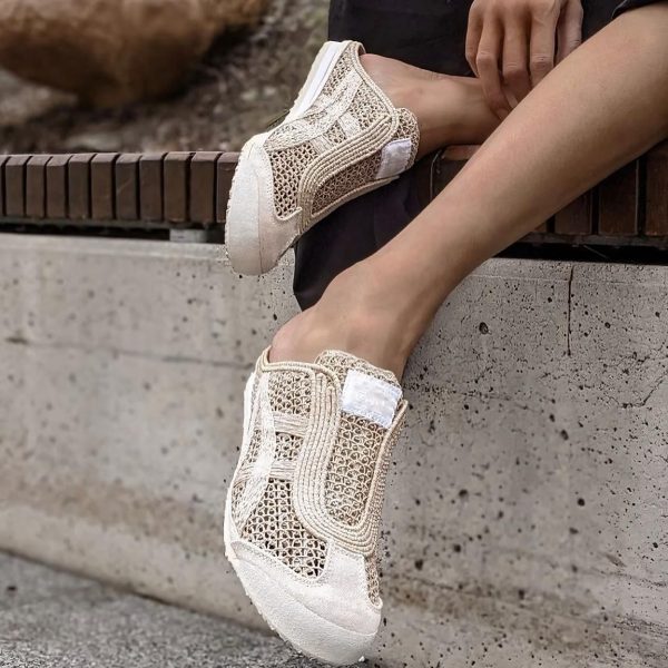 Cream-colored mesh sneakers on a person’s feet, resting on a wooden bench and concrete ledge outdoors