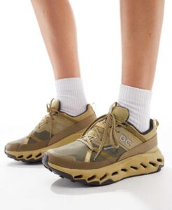 Beige athletic sneakers worn with white socks, shown from the side against a white background.