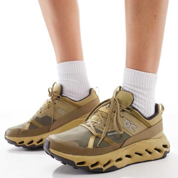 Beige athletic sneakers worn with white socks, shown from the side against a white background.