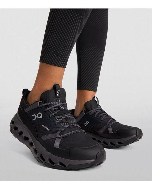 Black running shoes with a chunky, vented sole worn by a person in black patterned leggings.