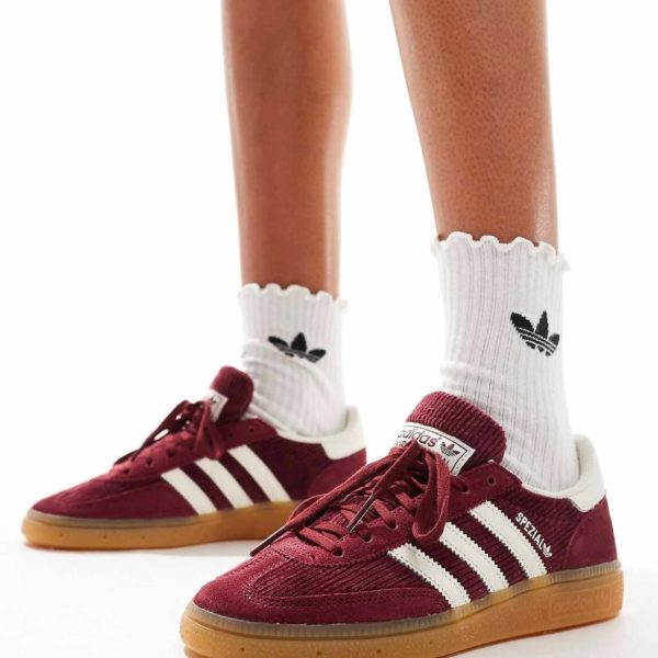 Person wearing maroon Adidas sneakers with white stripes and gum soles, paired with white ribbed socks.