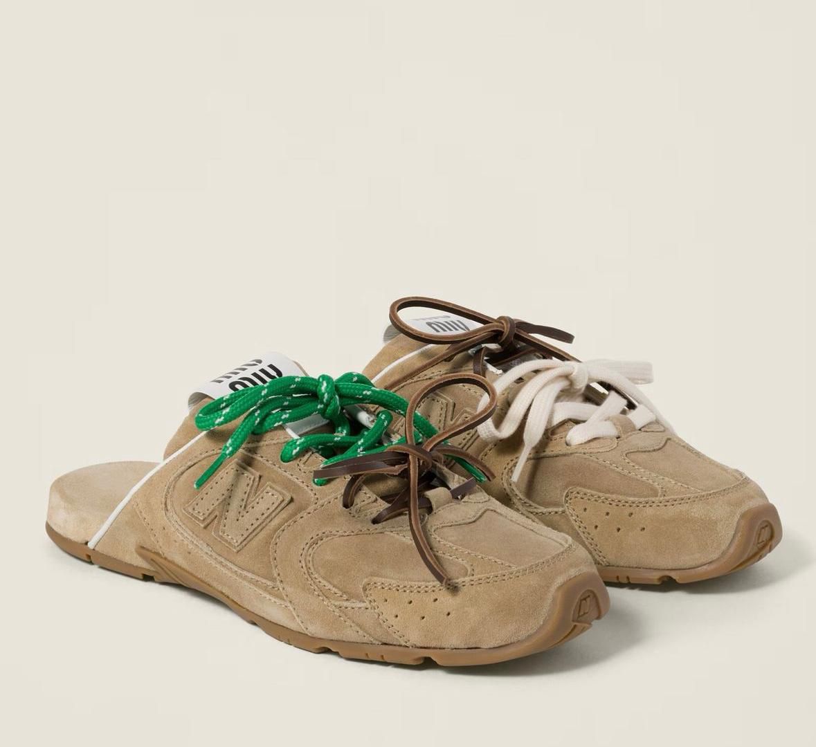 Beige suede sneakers with chunky soles and mismatched laces—green on the left shoe and white on the right.
