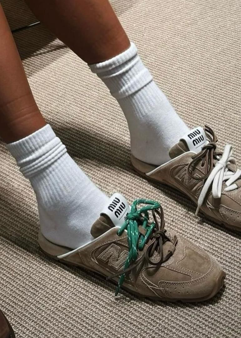 WhatsApp_Image_2024-12-30_at_12.17.00 | UAE SPORT STORE Person wearing white crew socks and beige sneakers with green laces on a carpeted floor, close-up of feet.