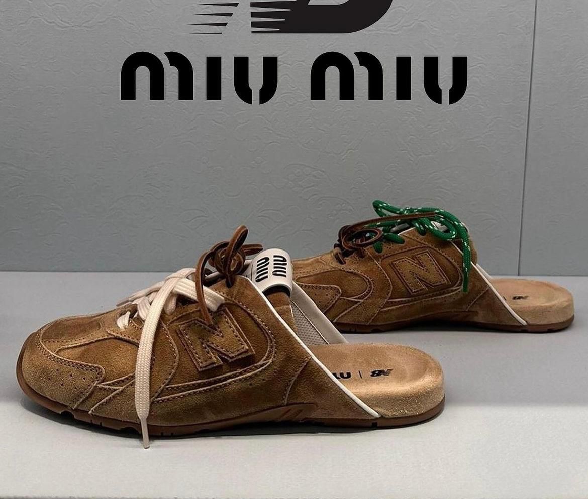 WhatsApp_Image_2024-12-30_at_14.44.28 | UAE SPORT STORE Two brown suede slides with cream and brown laces placed on a light surface, a Miu Miu sign visible in the background.