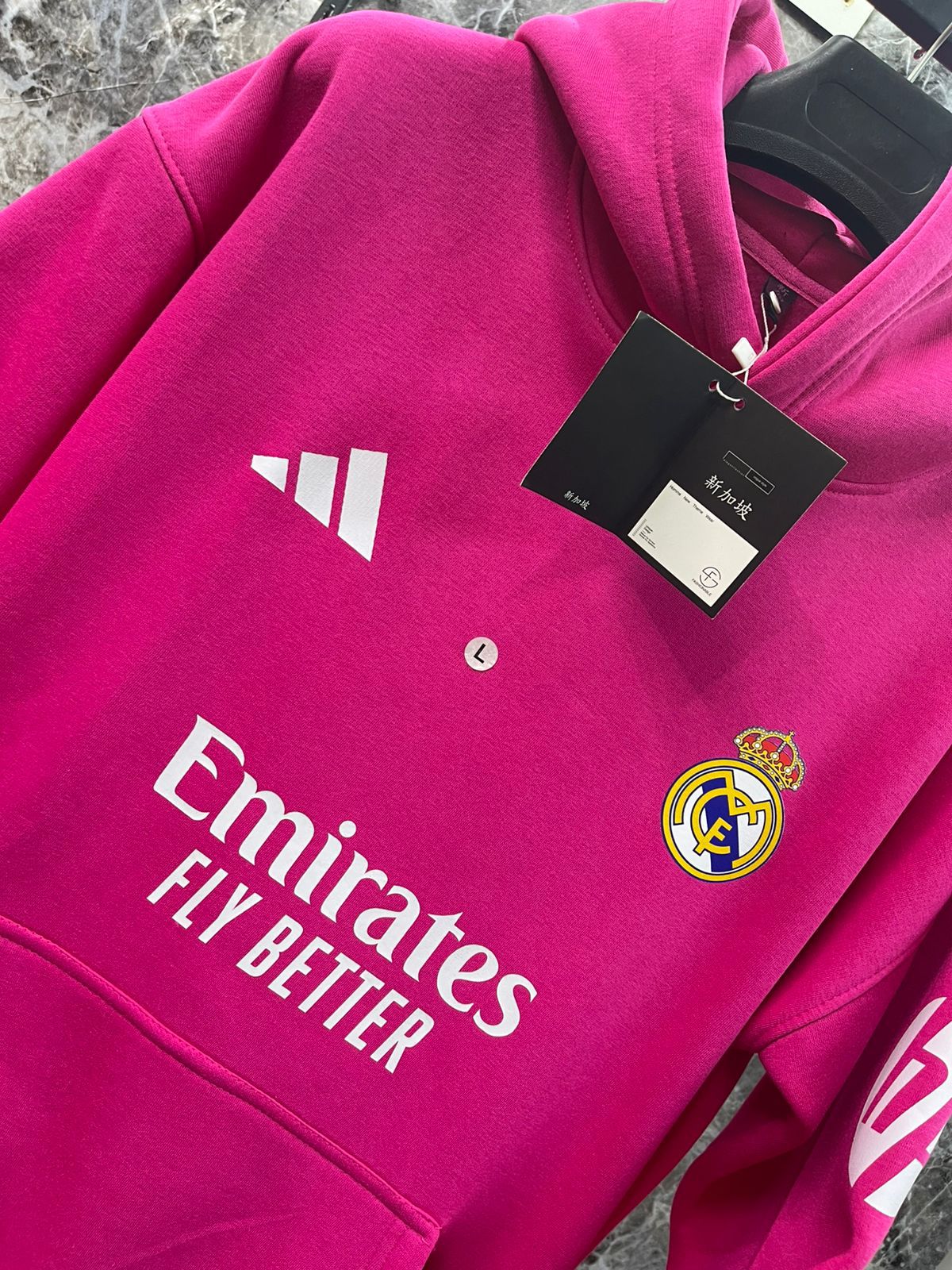 WhatsApp_Image_2025-01-10_at_18.40.05_1 | UAE SPORT STORE Bright pink Real Madrid hoodie with white Adidas-like logo and team crest, tag attached.