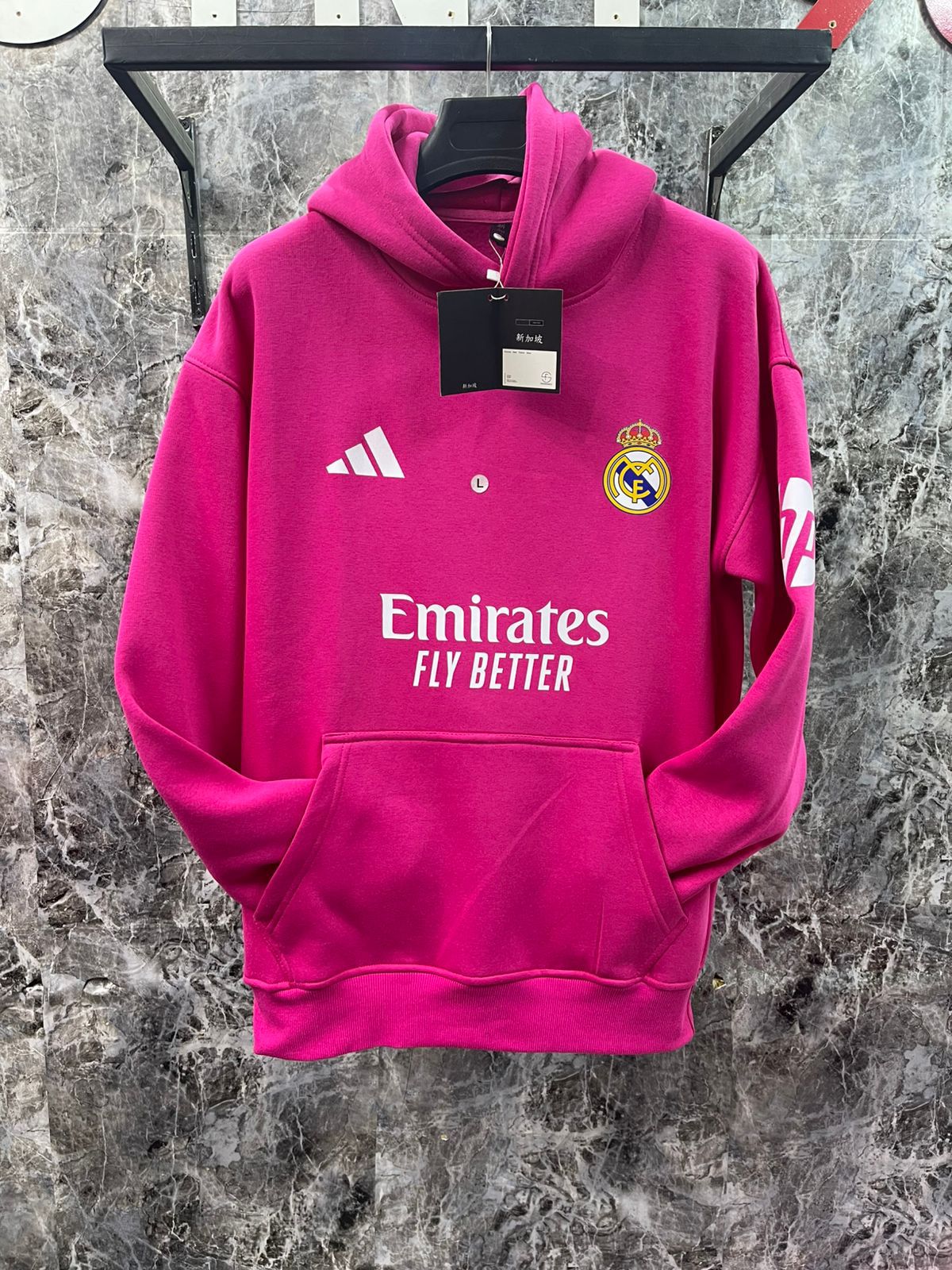 WhatsApp_Image_2025-01-10_at_18.40.05_2 | UAE SPORT STORE Bright pink Real Madrid hoodie on a hanger, showing Adidas logo, Real Madrid crest, and Emirates Fly Better branding with a front pocket.