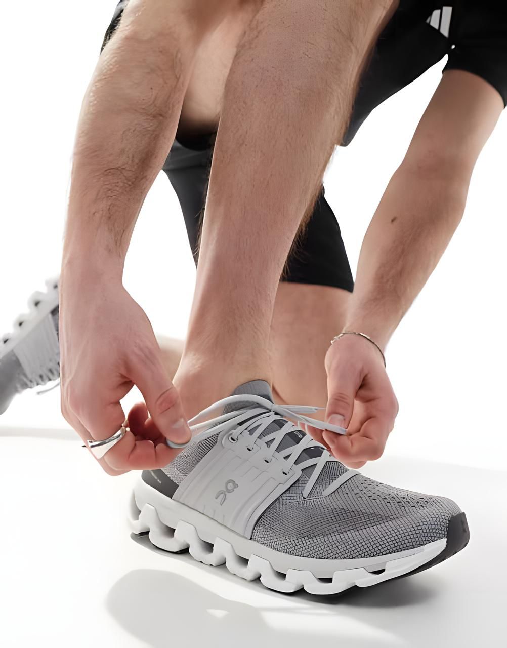 WhatsApp_Image_2025-01-13_at_21.03.18 | UAE SPORT STORE Close-up of hands tying the laces of a gray athletic shoe with a white sole.