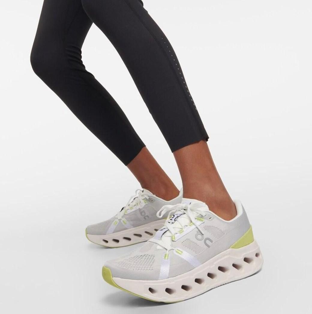 WhatsApp_Image_2025-01-18_at_13.18.14 | UAE SPORT STORE Athletic white and light gray sneakers with lime accents and a perforated chunky sole being worn with black leggings by a person walking forward.