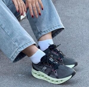 WhatsApp_Image_2025-01-19_at_11.58.59 | UAE SPORT STORE Close-up of feet in dark athletic sneakers with a mint-green chunky sole, white socks, and cuffed light-wash jeans.