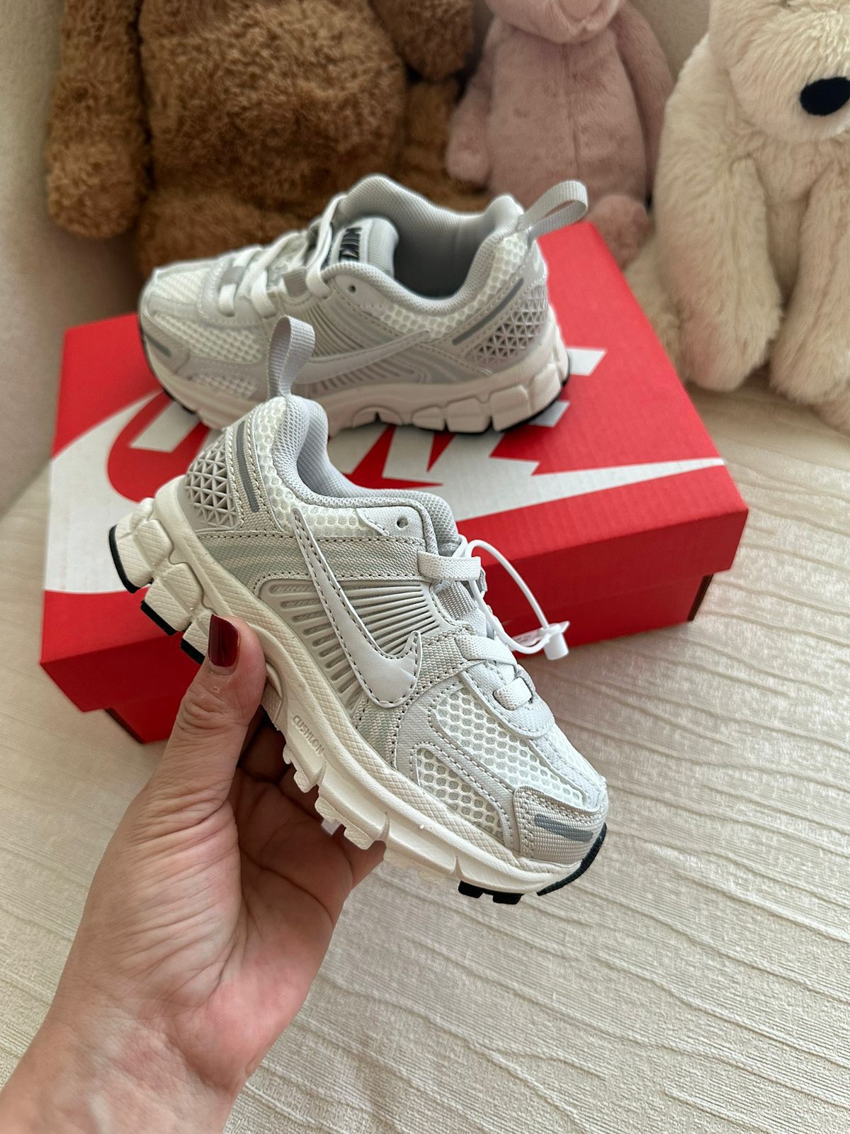 WhatsApp_Image_2025-01-21_at_21.52.32 | UAE SPORT STORE White Nike toddler sneakers with mesh panels resting on a red Nike shoebox, plush toys in the background.