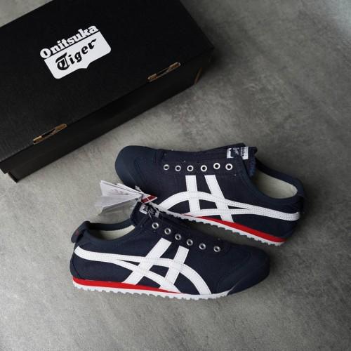 Pair of navy blue Onitsuka Tiger sneakers with white stripes and red sole, placed beside a black Onitsuka Tiger shoebox on a gray surface, tag still attached.