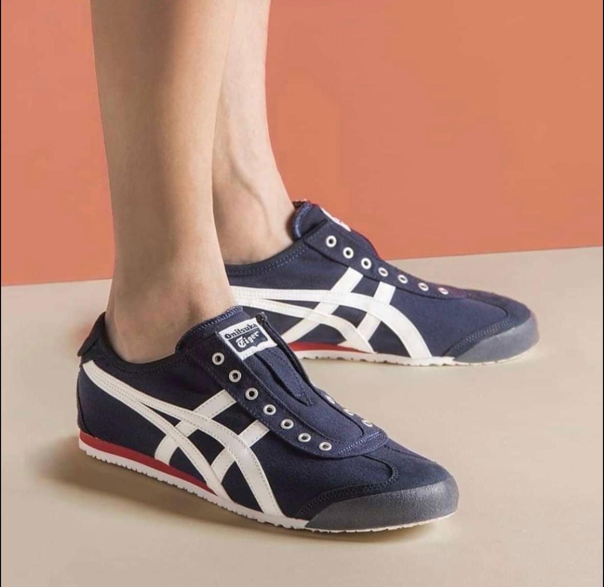 WhatsApp_Image_2025-02-11_at_17.14.54 | UAE SPORT STORE Pair of navy blue sneakers with white stripes on the feet of a person, standing on a light floor.
