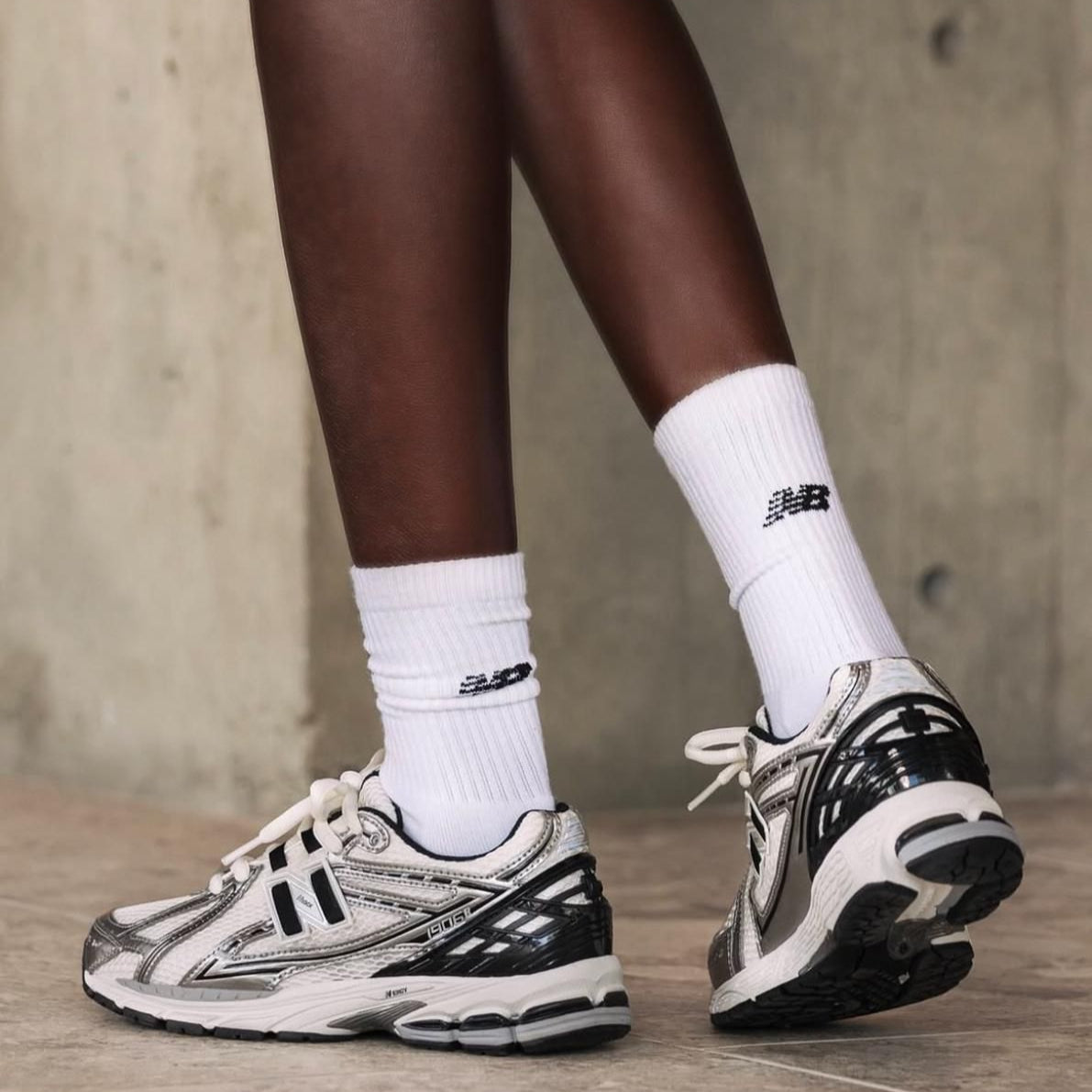 WhatsApp_Image_2025-02-13_at_14.22.28 | UAE SPORT STORE Person wearing white crew socks and silver-gray running shoes standing on a concrete floor.
