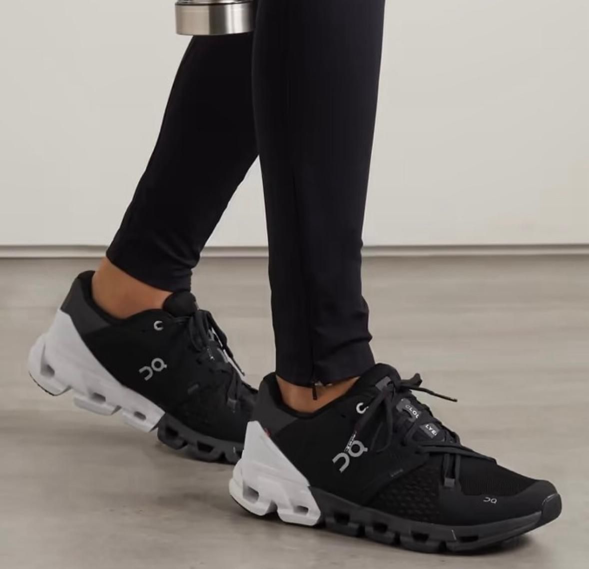 WhatsApp_Image_2025-02-16_at_13.15.52 | UAE SPORT STORE Close-up of black and white On running shoes on a person’s feet indoors; black upper, chunky white sole, logo visible on side.