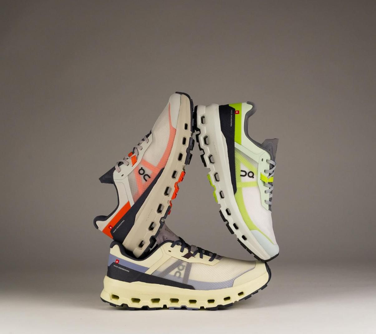WhatsApp_Image_2025-02-22_at_11.32.53 | UAE SPORT STORE Three colorful running shoes balanced in a sculptural loop against a gray background.