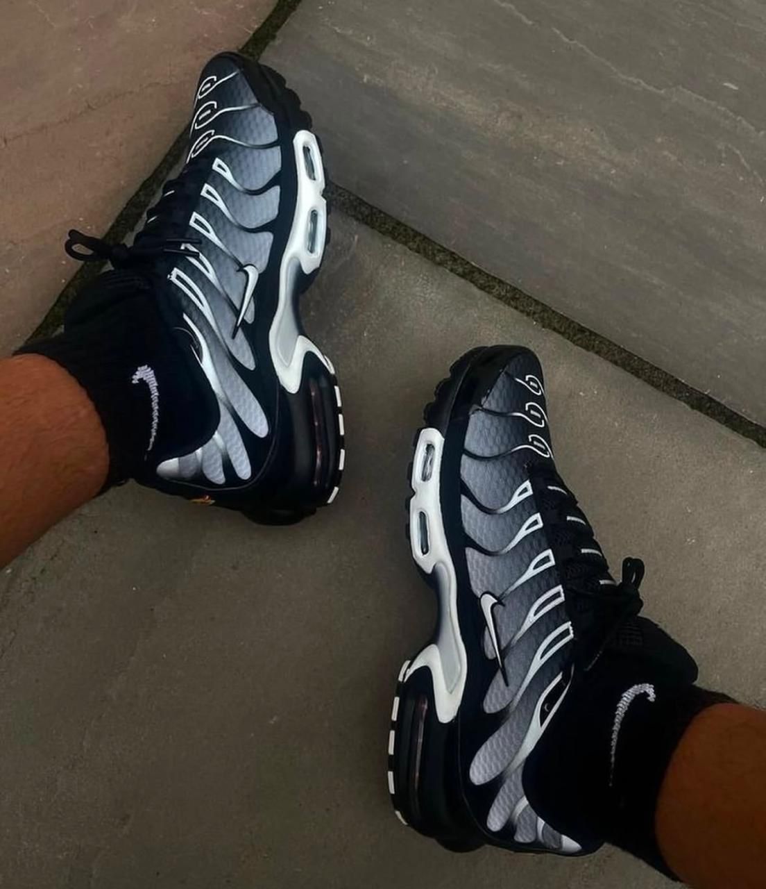 WhatsApp_Image_2025-02-24_at_12.27.35 | UAE SPORT STORE Pair of dark gray and black Nike running shoes with white accents on a tiled floor.
