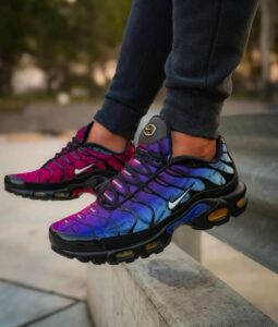 WhatsApp_Image_2025-02-25_at_11.05.47 | UAE SPORT STORE Person wearing colorful gradient Nike sneakers (pink, purple, blue) balancing on a concrete ledge outdoors with dark joggers nearby.