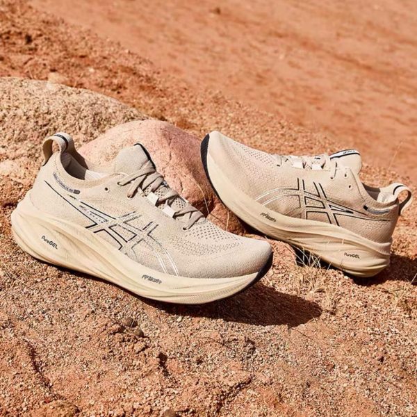 Beige ASICS running shoes resting on sandy, rocky desert terrain.