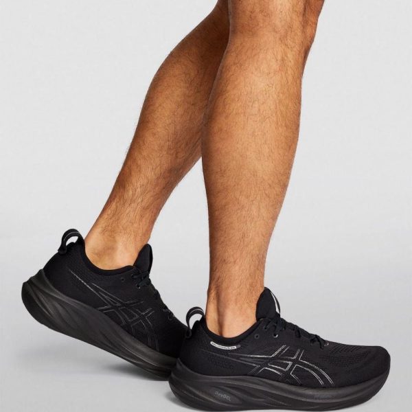 Black running shoes worn by a person, showing the side and sole details with a cushioned black sole and knit upper.