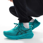 Turquoise running shoes with laces, white socks, and black joggers in a crouched stance, close-up view