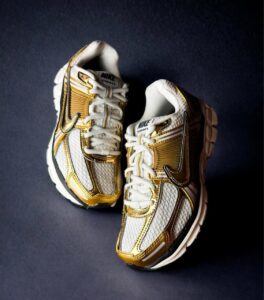 WhatsApp_Image_2025-04-03_at_16.32.52_1 | UAE SPORT STORE Pair of white and gold Nike VOMERO 5 running shoes on a dark background.