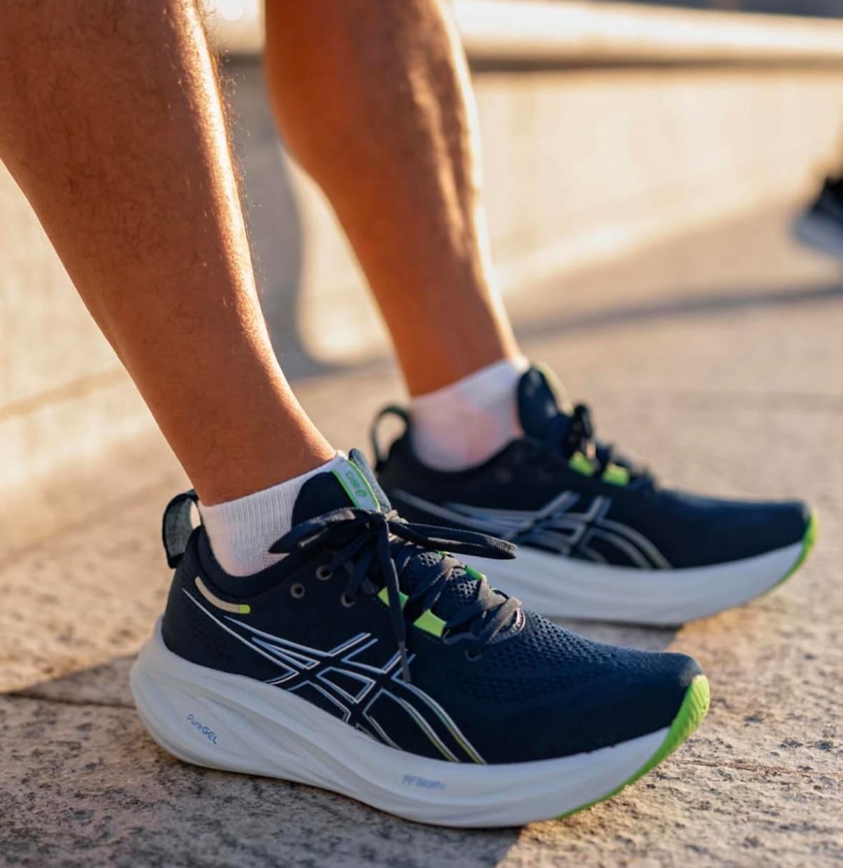 WhatsApp_Image_2025-04-04_at_14.42.33 | UAE SPORT STORE Close-up of a runner's navy blue ASICS shoes with white thick soles and neon green accents on a concrete surface.