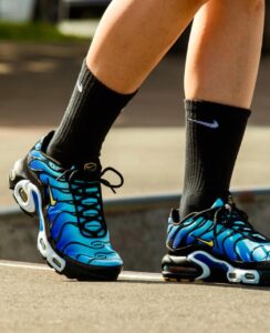 Close-up of blue Nike running shoes with black laces and yellow swoosh on a person wearing black socks