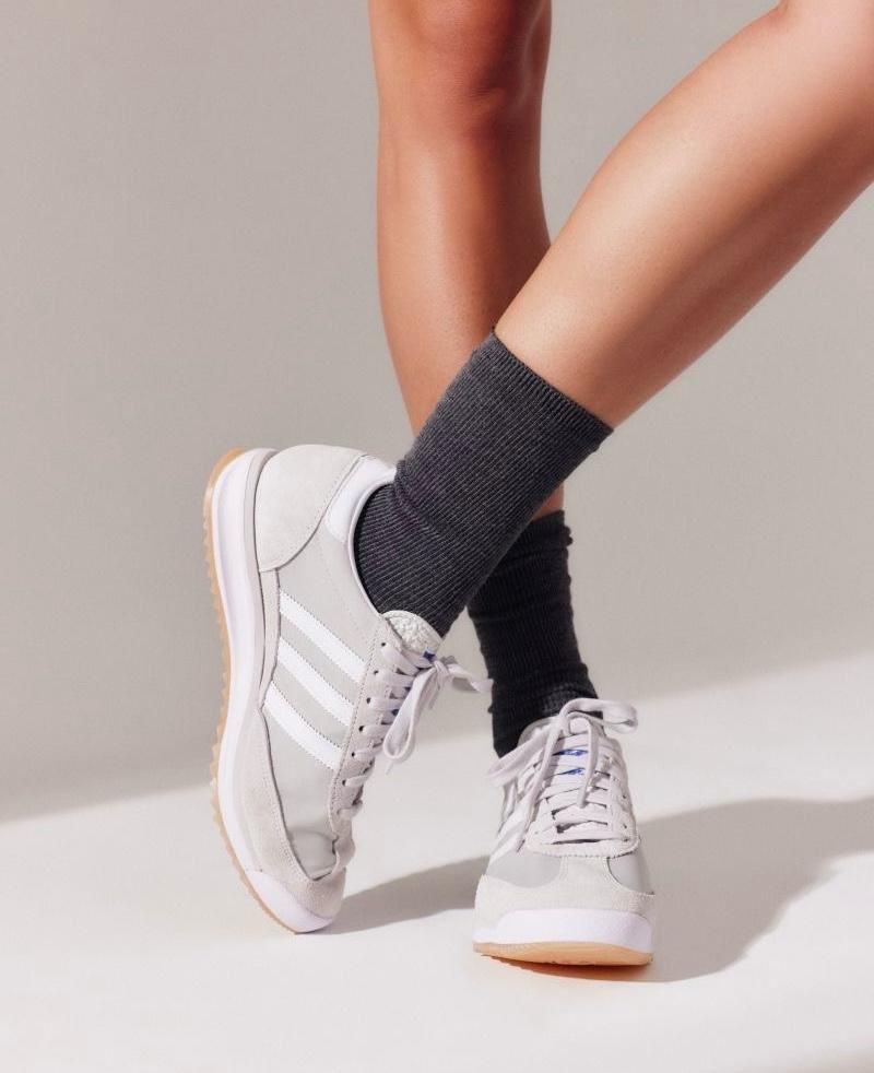 WhatsApp_Image_2025-04-08_at_14.47.26 | UAE SPORT STORE Two legs wearing light gray sneakers and dark gray socks, one foot crossed over the other.