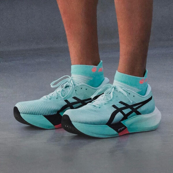 Mint teal running shoes with black Asics logo, paired with matching teal socks, on a gray floor.