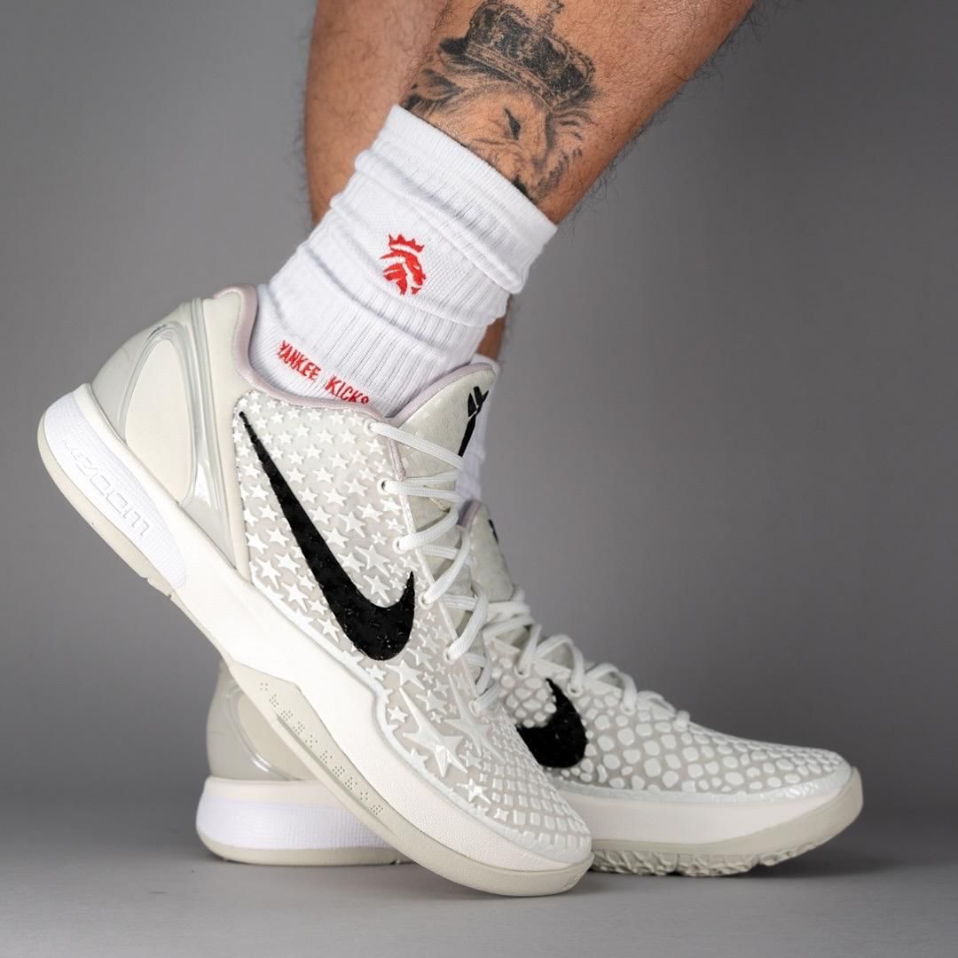 WhatsApp_Image_2025-05-21_at_13.39.34 | UAE SPORT STORE White Nike basketball sneakers with a star-patterned upper and black swoosh, worn on a model's foot with white crew socks.