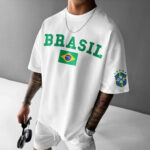 Model wearing a white Brazil T-shirt with BRASIL text and Brazil flag, featuring a CBF emblem on the sleeve and holding headphones.