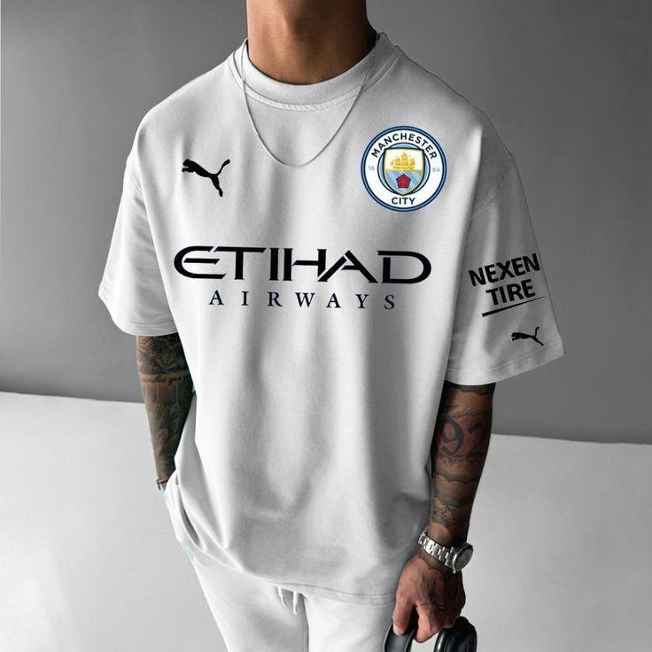 WhatsApp_Image_2025-06-29_at_19.52.19_1 Person wearing a white Manchester City football jersey with Etihad Airways sponsor and club crest on the chest, plus Puma logos and a sponsor on the sleeve.