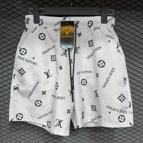 White shorts with Louis Vuitton monogram print hanging on a black hanger on a textured background.