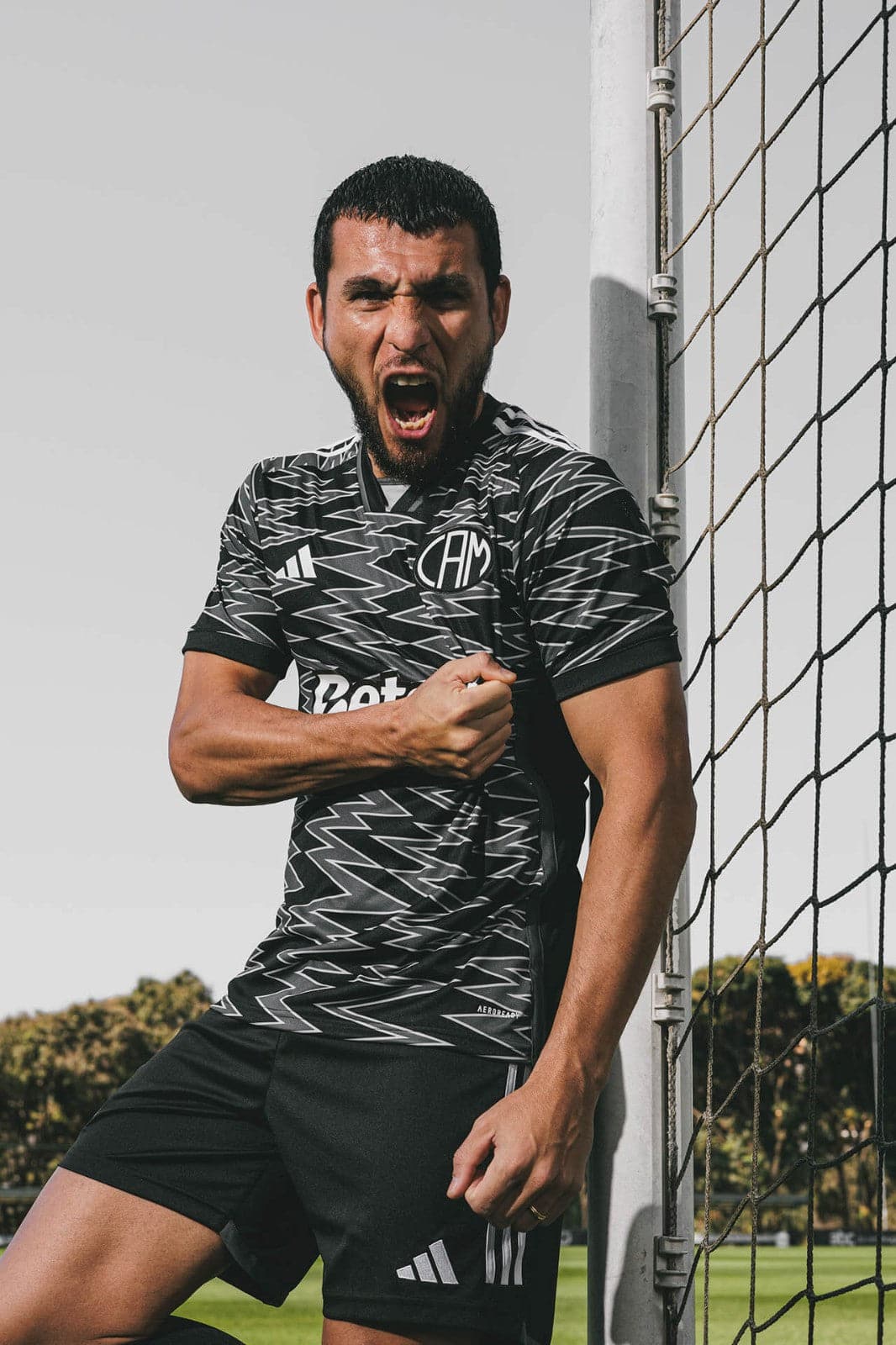 X6wtzsYT2yswvQr | UAE SPORT STORE Male soccer player leaning against a goalpost, shouting with a clenched fist in a patterned jersey.