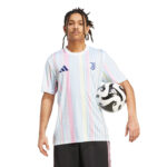 Man wearing a pastel-striped Juventus football jersey, holding a soccer ball under his arm.