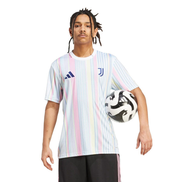 Man wearing a pastel-striped Juventus football jersey, holding a soccer ball under his arm.