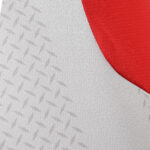Close-up of light gray fabric with a repeating diamond texture and a red curved edge/section.