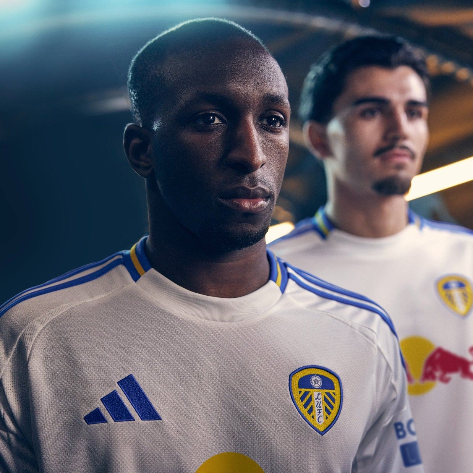XjeCoYBUctyUqgH | UAE SPORT STORE Close-up of a Leeds United player in a white jersey with blue trim, standing in a stadium.