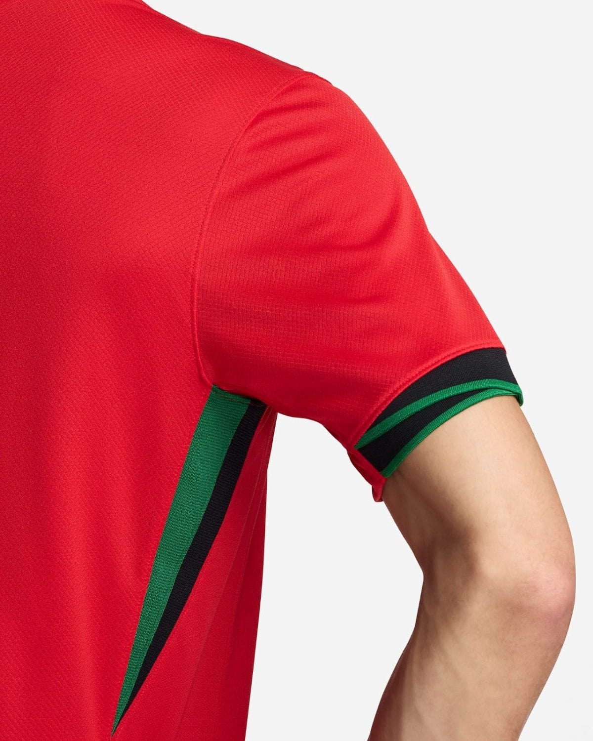 Close-up of a red sports jersey sleeve with green and black trim/piping.