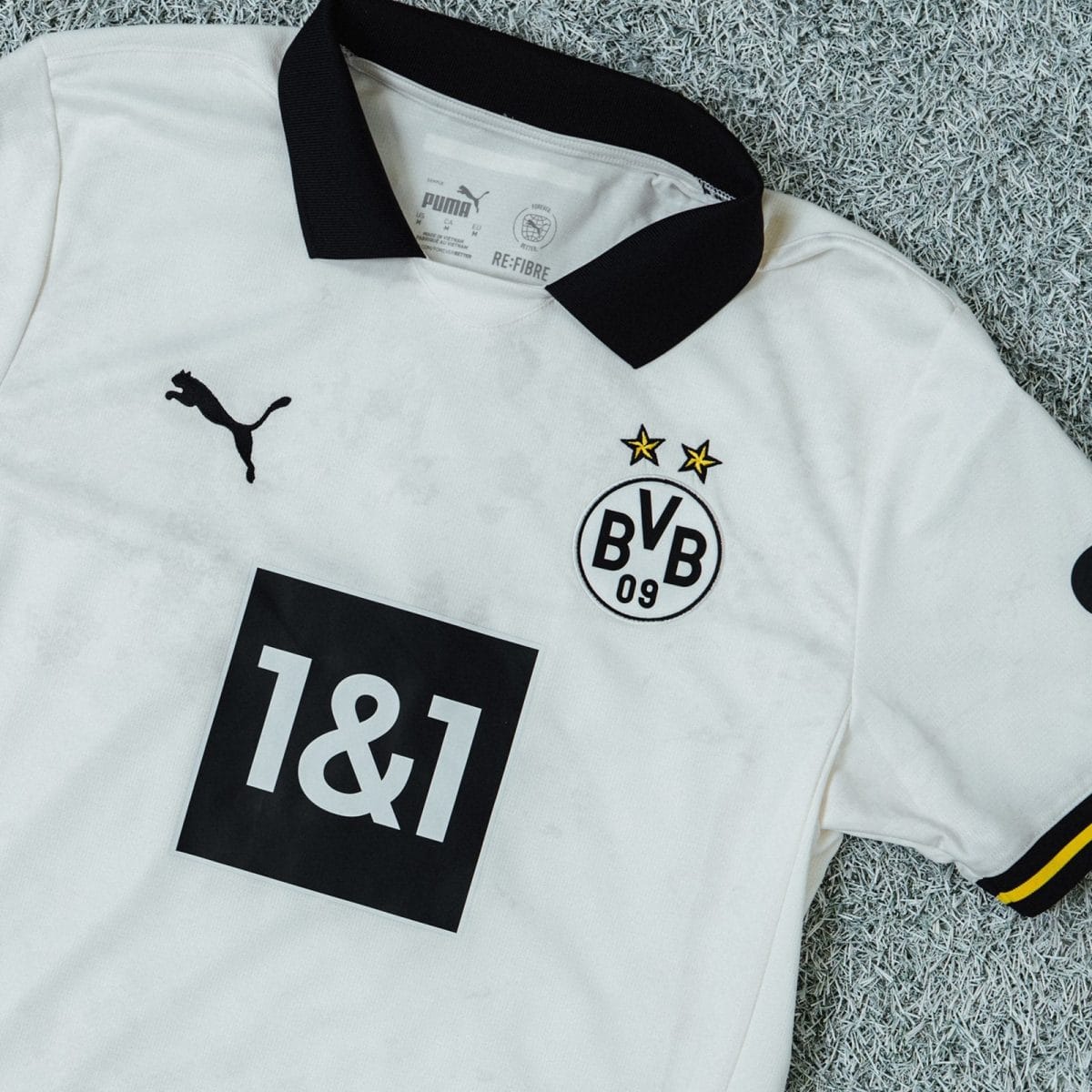 White Borussia Dortmund football jersey with black collar, crest, Puma logo, and race bib number 18 on it.
