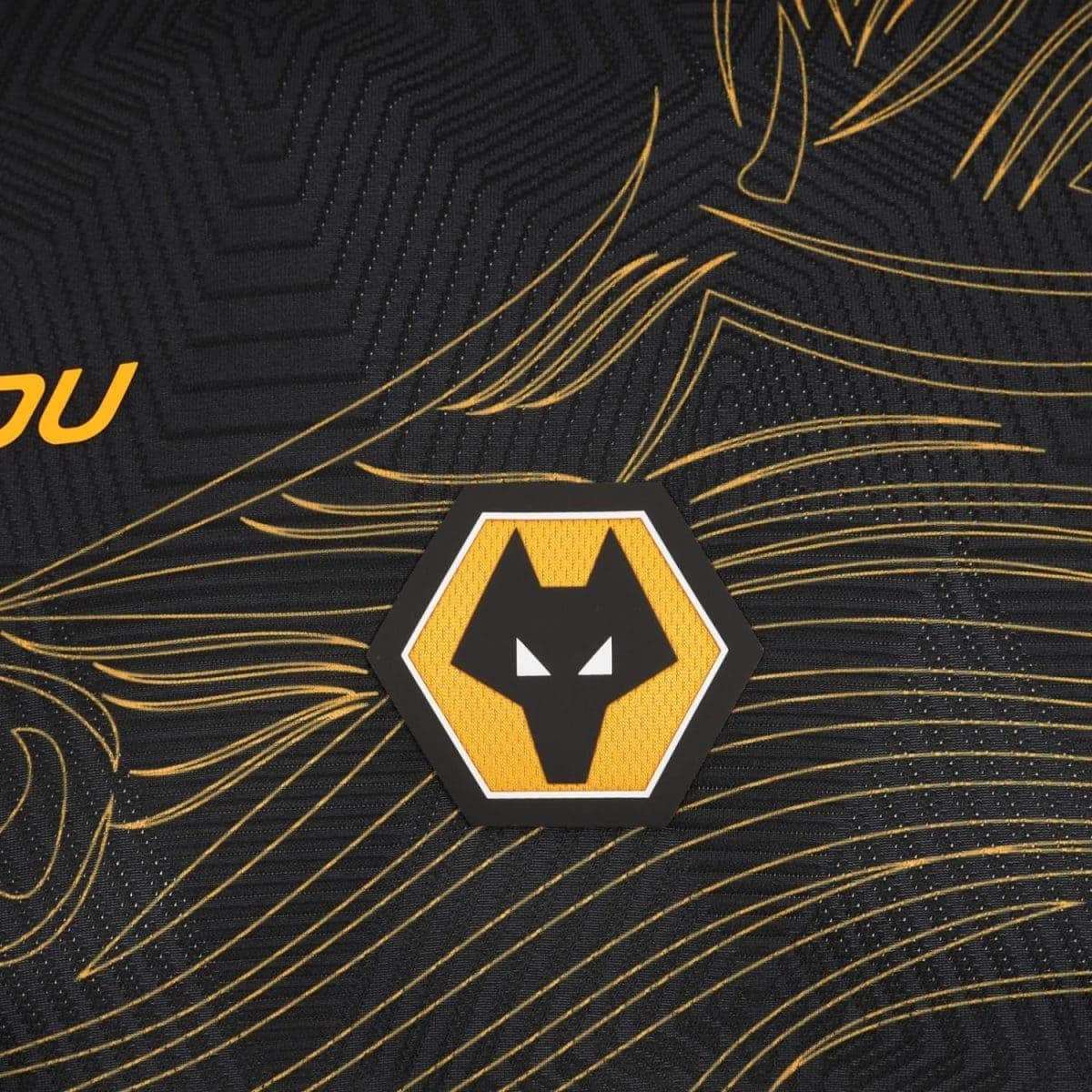 Close-up of a hexagonal yellow and black wolf head emblem on a black patterned fabric with gold lines, likely a team logo.